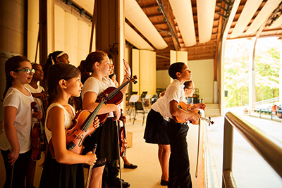  Smiling young musicians on stage with instruments on hand