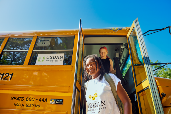 Student walking off the bus and smiling