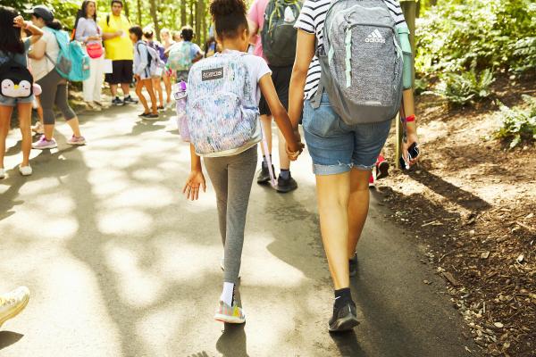 Two children walking away from the camera, holding hands