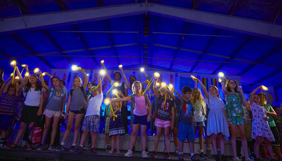Children standing on stage holding lights and waving them in the air. Children standing on stage holding lights and waving them in the air.