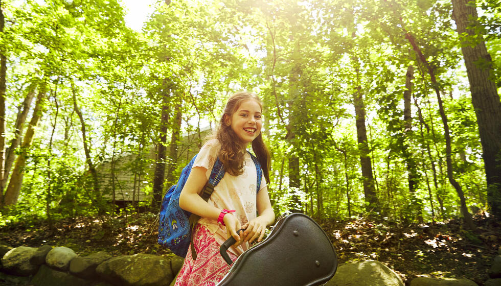 Girl in the woods holding a violin. 