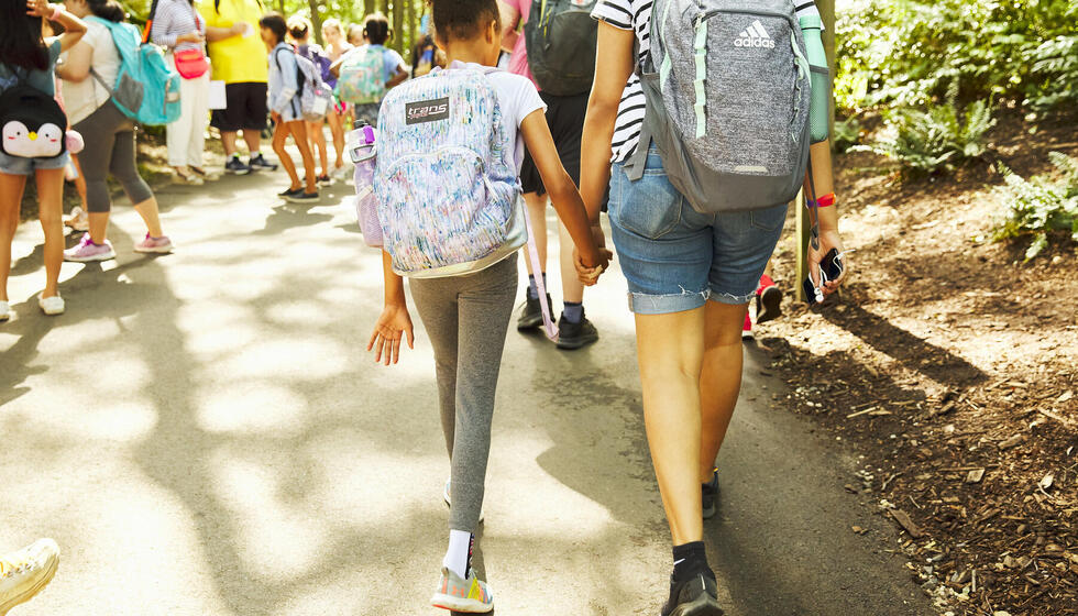 Two children walking away from the camera, holding hands. Two children walking away from the camera, holding hands.