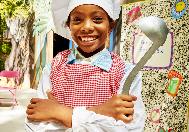 Young smiling girl dressed in a chef's costume and holding a ladle Young smiling girl dressed in a chef's costume and holding a ladle