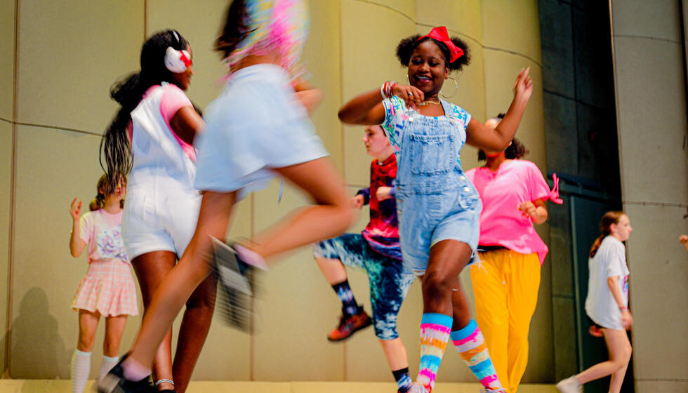 Group of students dancing in a circle on stage.