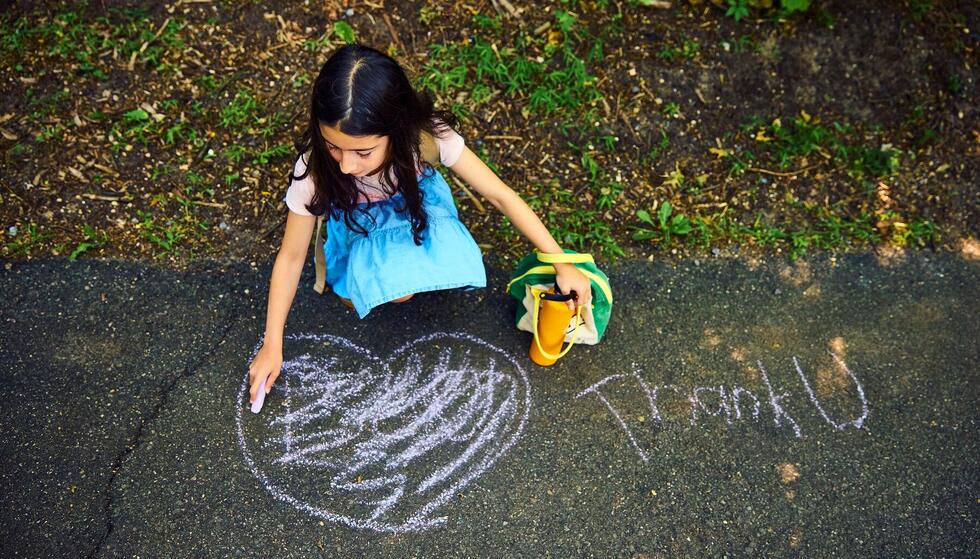 Student drawing "Thank U" in chalk