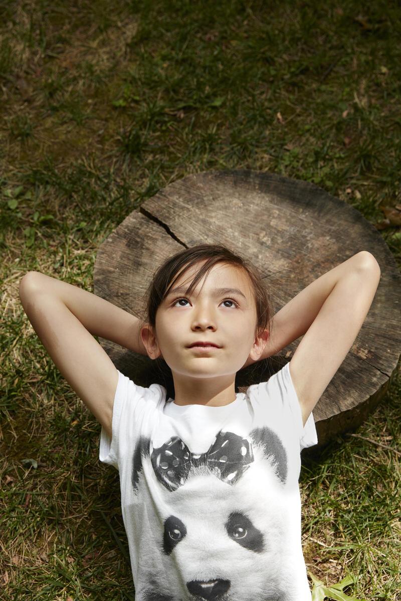 Young girl lying on a log with her hands behind her head