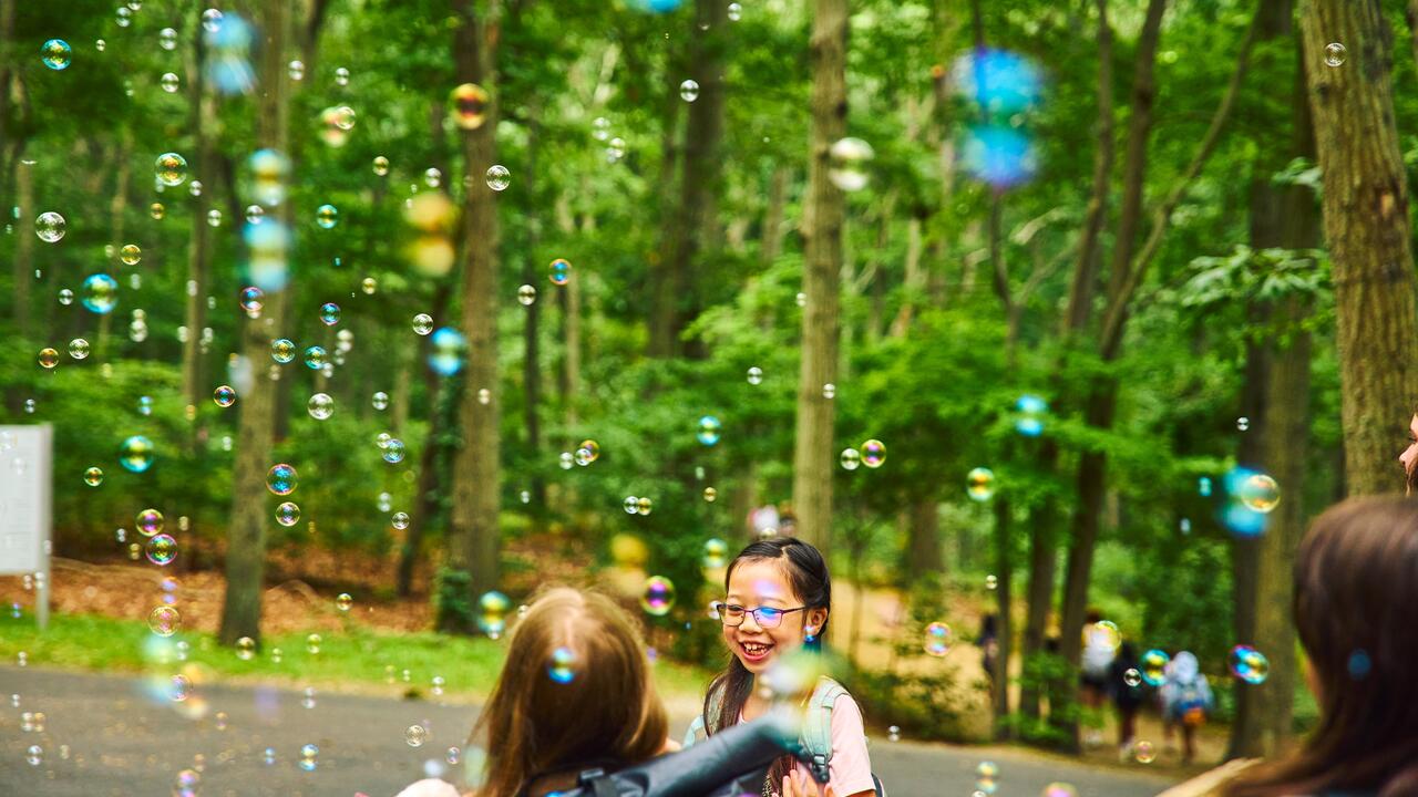 Usdan Summer Camp for the Arts students celebrate under the bubbles. Two students celebrate under the bubbles.