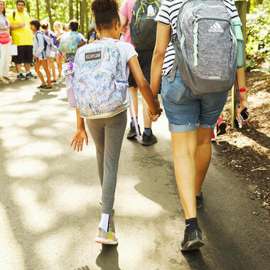 Outdoor Long Island summer camp. Students walking hand-in-hand.