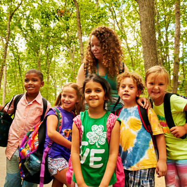 Group of children standing in the woods smiling.