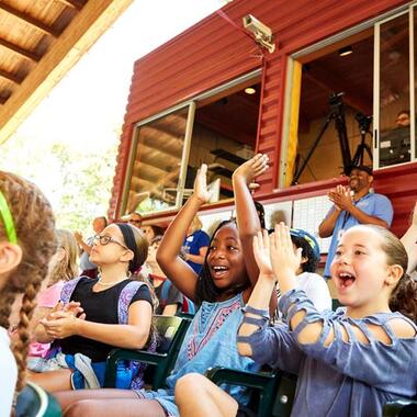 A group of students sitting in the audience smiling, clapping, and cheering. A group of students sitting in the audience smiling, clapping, and cheering.