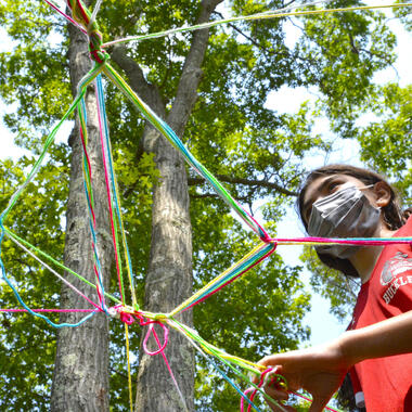 Students standing under yarn sculpture. Students standing under yarn sculpture.