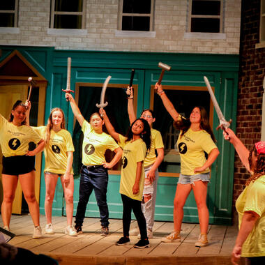 students on stage with swords students on stage with swords