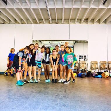 Students standing in theater studio, smiling