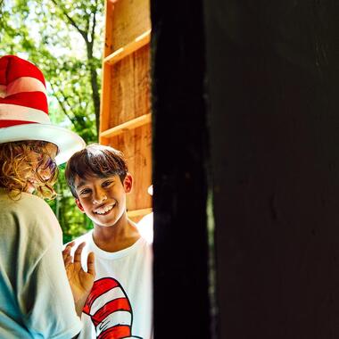 Student backstage waving and smiling.