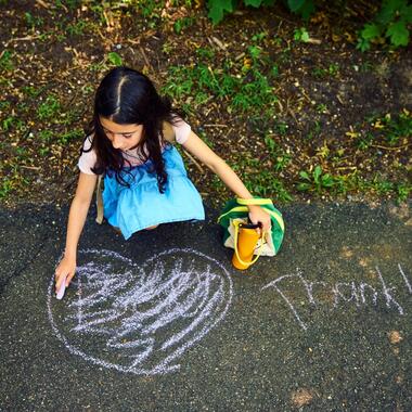 Student drawing "Thank U" in chalk